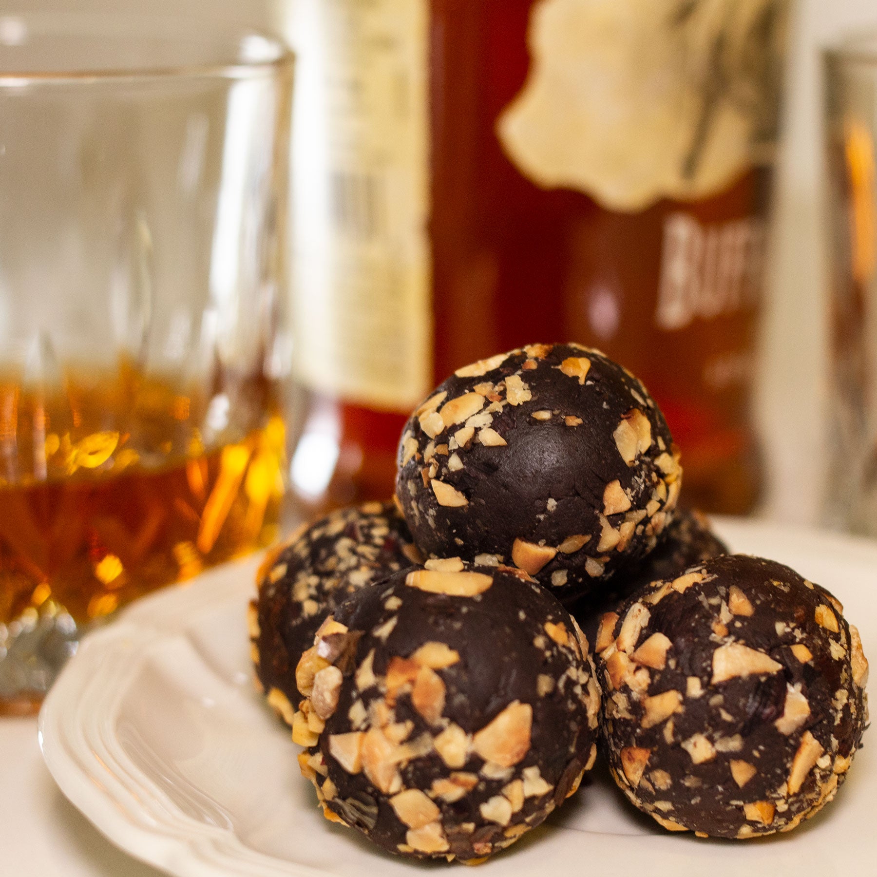 Decadent chocolate liqueur balls dessert in front of a glass of whiskey